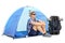 Cheerful male hiker sitting in front of a tent