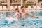 Cheerful man and child swim in the pool