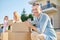 Cheerful man crouched near boxes on street