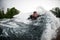 Cheerful man lying on wake surfboard rides on wave from motor boat