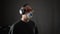 Cheerful man in medical mask and headphones enjoying music on black background. Happy man in protective mask listening