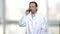 Cheerful man in white coat talking on phone.