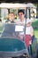 Cheerful man and woman golfers riding golf cart