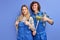 cheerful man and woman plumbers in blue uniform with plunger tool, being glad to repair bathtub for clients