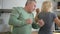 Cheerful married couple dancing in modern kitchen interior.