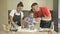 Cheerful married couple with a little daughter, cook some dough together, enjoy family activities.