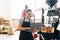 Cheerful master working with special equipment. Man controlling brown beans pouring into cooler machine from large coffee roaster