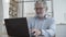 Cheerful mature businessman using laptop in co-working interior