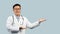 Cheerful mature chinese man doctor in white coat, glasses point hands to empty space