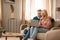 Cheerful Mature Couple Using Laptop Sitting On Sofa At Home