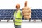 Cheerful mature male engineer showing thumbs up at a solar farm