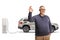 Cheerful mature man gesturing ok sign and charging electrical vehicle