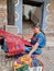 Cheerful mayan indian woman wearing a traditional huipil crafting handmade weavings in the city of Antigua in Guatemala.