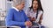 Cheerful Mexican caregiver talking to elderly patient with tablet