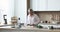 Cheerful middle aged dancing woman preparing salad in home kitchen