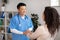 Cheerful middle aged korean doctor shaking hands, greets and supports black millennial female patient