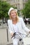 Cheerful middle-aged woman cycling in town