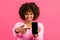 Cheerful millennial african american curly lady with braces show finger at phone with empty screen