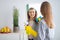 Cheerful millennial housewife wiping mirror with rag, using spray detergent to clean looking glass at home