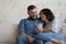 Cheerful millennial married couple sharing smartphone, holding cell phone