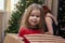 Cheerful mischievous girl posing in box from under the Christmas