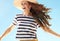 Cheerful modern woman in straw hat against blue sky jumping