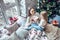 Cheerful mom and her cute daughter girl exchanging gifts near window