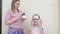 Cheerful mother and daughter dye their hair and do highlighting at home.