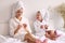 Cheerful mother and daughter filing nails on bed