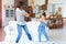 Cheerful mother with little daughter dancing at favourite song in living room at home