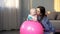 Cheerful mother playing with infant, making baby fitness exercises on big ball