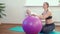 Cheerful mother playing with infant, making baby fitness exercises on big ball