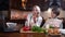 Cheerful mother and son cooking dinner and talking on laptop. Portrait of joyful Caucasian family of bloggers preparing