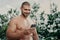 Cheerful motivated shirtless sportsman concentrated in smartphone, sends text messages, uses wireless earphones for listening
