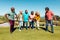 Cheerful multiracial seniors playing rugby in yard against clear blue sky at retirement home