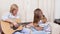 Cheerful musician mother sitting on sofa with daughter