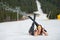 Cheerful naked female skier is lying on snowy slope near ski lift at resort