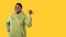 Cheerful Obese Black Woman Pointing Thumb Finger Aside, Yellow Background