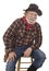 Cheerful old cowboy sits on a stool