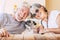 Cheerful old senior couple smile and enjoy her best friend dog pug with love - concept of happy mature people and animal - joy
