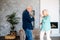 Cheerful older spouses dancing at living room