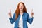 Cheerful outgoing alluring redhead woman, long red hairstyle, showing top promo, pointing fingers up and laughing