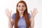 Cheerful outgoing smiling redhead woman in t-shirt, raising hands and waving them in hello, hi gesture, greeting happily