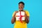 Cheerful Oversized African Woman Holding Gift Box On Blue Background