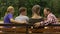 Cheerful parents and their teenage children planning weekend on bench in park