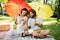 Cheerful parents with two kids have a rest on the lawn under the bright red and yellow umbrellas covering them from the