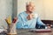 Cheerful pensioner drinking tea while sitting at the table