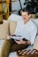 Cheerful pensioner in glasses reading newspaper while sitting