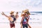 Cheerful people having fun in summer holiday vacation - group of young millennial tourists langh at the beach - men carrying woman