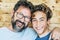 Cheerful people portrait with father and son hug and laughing a lot together having fun and looking at the camera - wooden